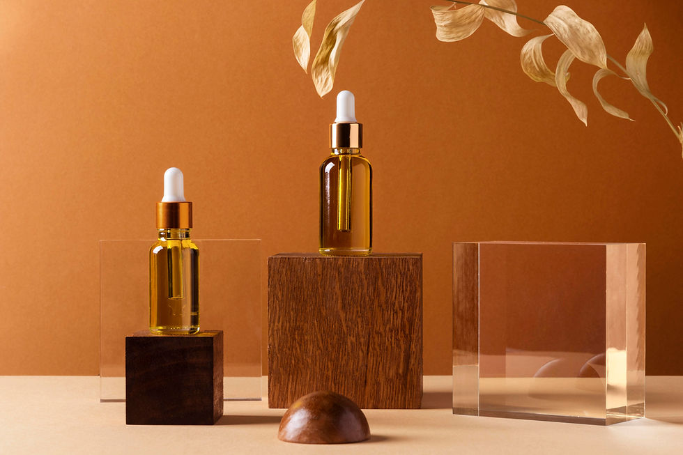 Two amber dropper bottles on wooden blocks against a warm brown background. Dried leaves hang above, creating a natural, serene vibe.