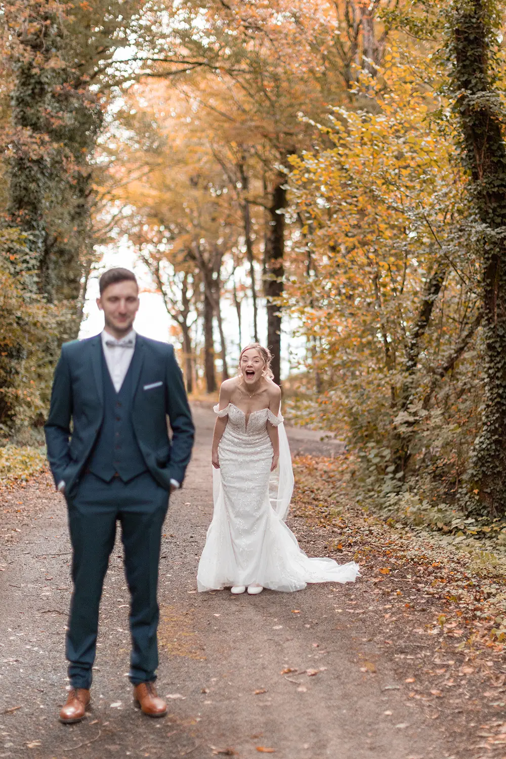 Le marié attend la mariée qui rigole derrière lui lors de leur first look en automne 
