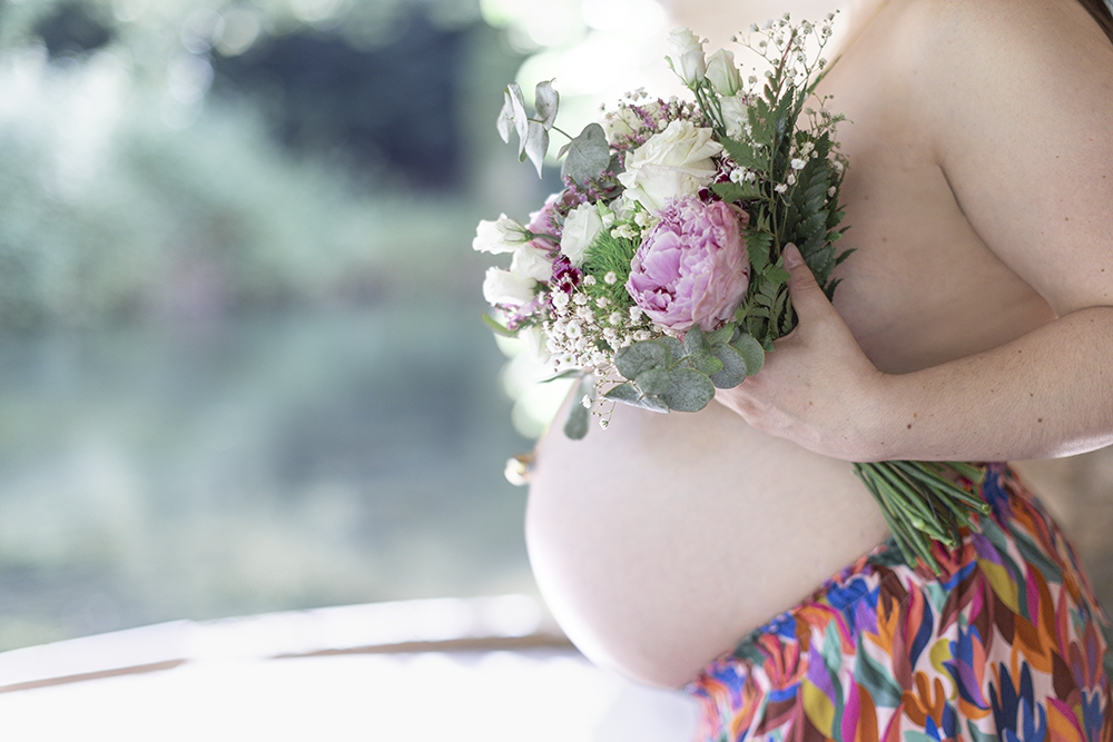 Ventre arrondi de femme enceinte avec un bouquet de fleurs
