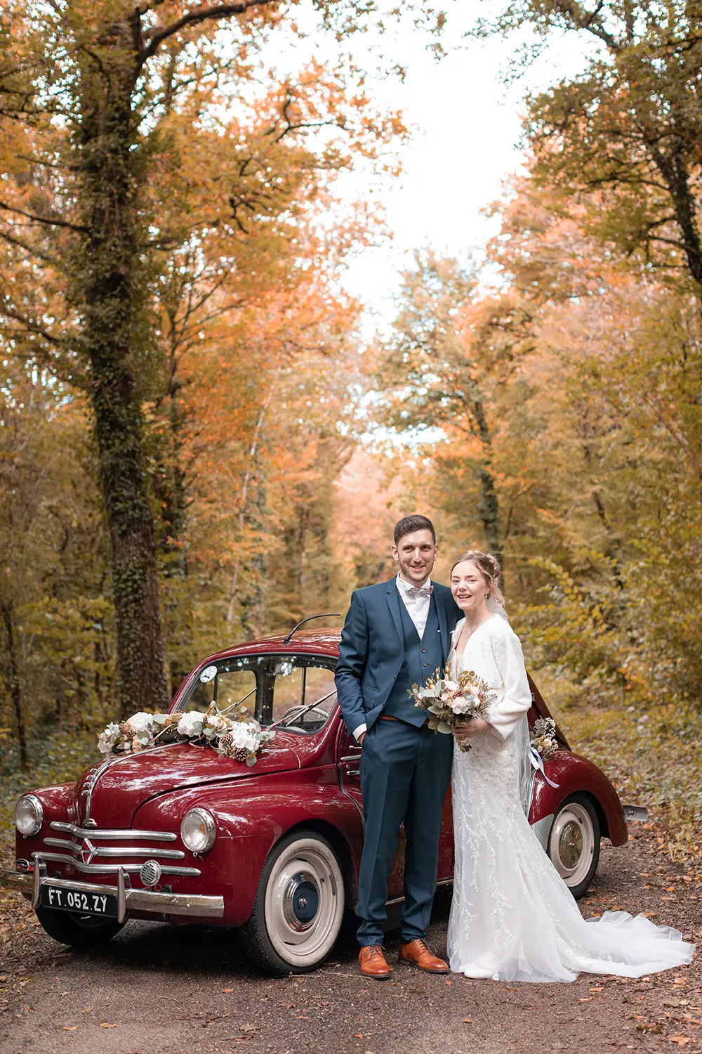 Les mariés s'enlacent devant leur voiture vintage de collection dans la forêt d'Haguenau en automne
