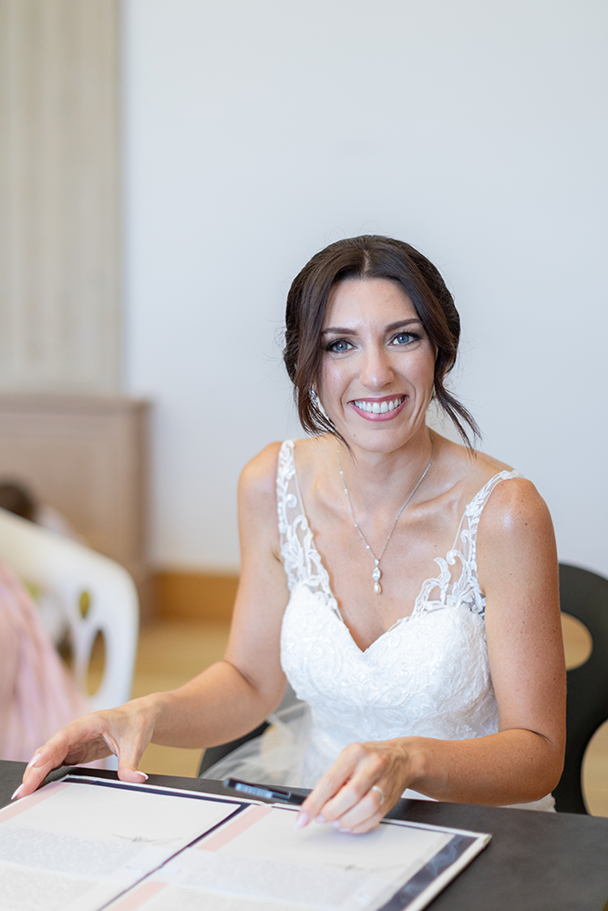 La mariée sourit et signe le registre