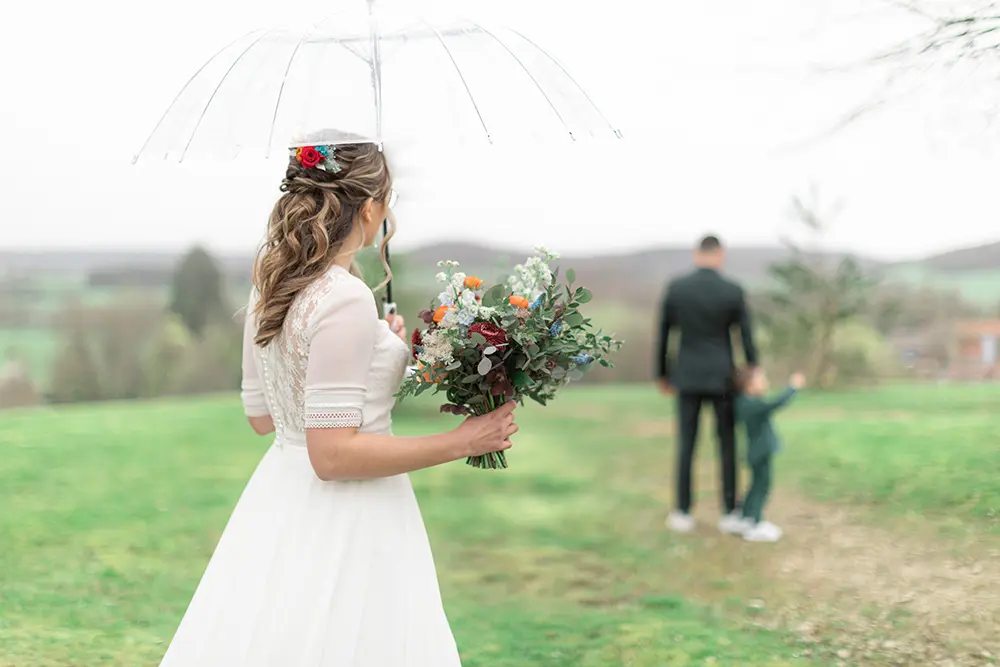 La mariée arrive pour son first look avec un parapluie transparent