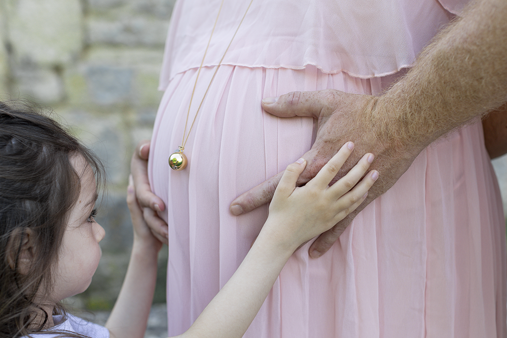 Les mains de papa et de Eva qui caressent le ventre arrondi de maman
