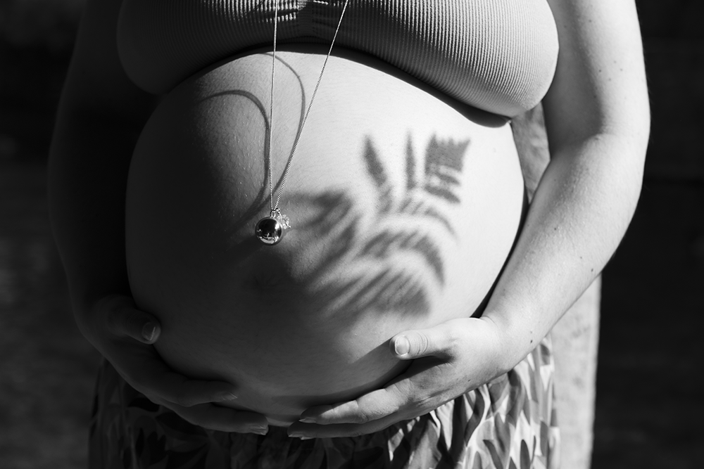 Le ventre arrondi de la future maman avec une ombre de feuillage