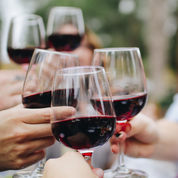 People toasting with glasses of red wine.