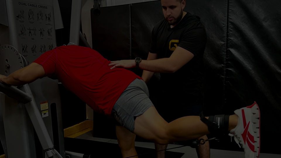 A personal trainer at DEGL Fitness in Houston, Texas, guiding a client through a cable machine glute kickback exercise. This highlights DEGL Fitness’s focus on proper technique and individualized training to achieve fitness goals | DEGL Fitness.
