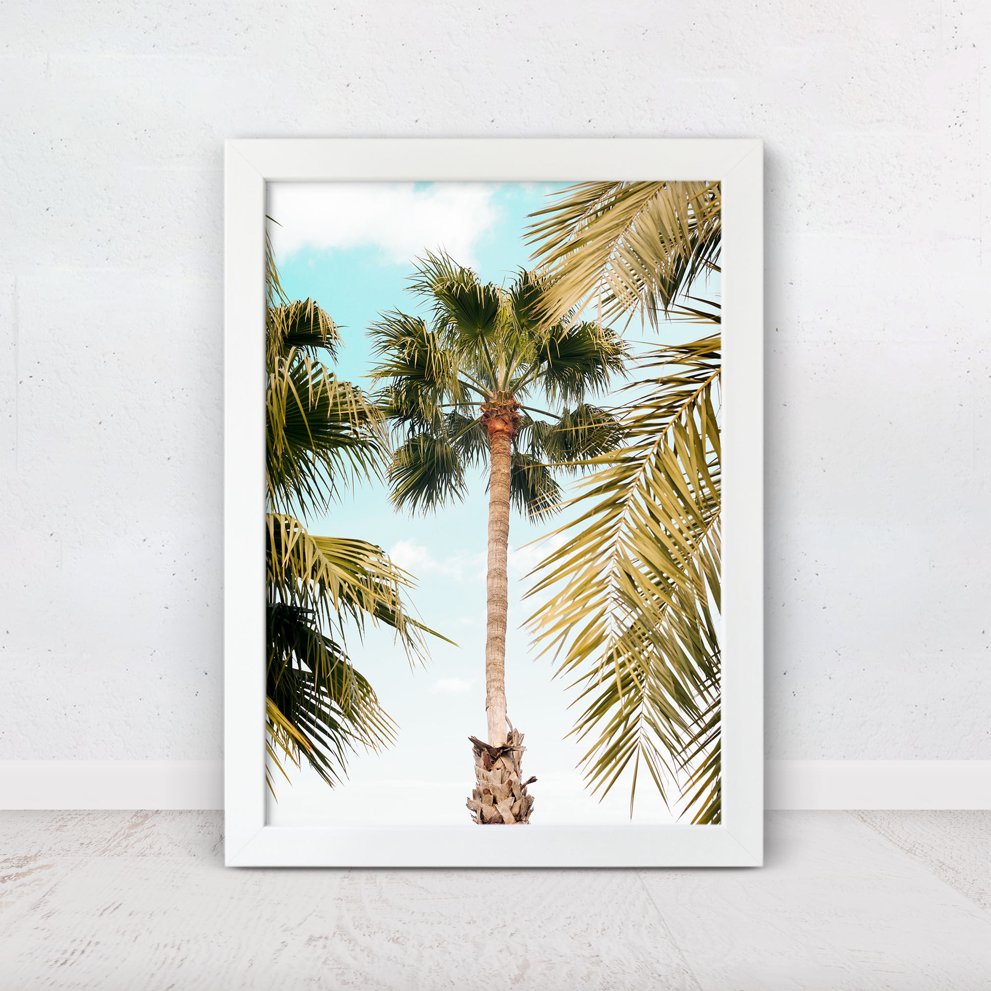 Palm tree viewed from below with blue sky and tropical leaves
