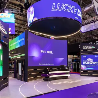 Commanding Presence with Curved LED Screens
A sweeping curved LED wall dominates the stand’s main façade, projecting bold messages like “SAVE TIME” with clarity and style. The elevated overhead ring screen adds vertical dimension, ensuring visibility from across the venue.