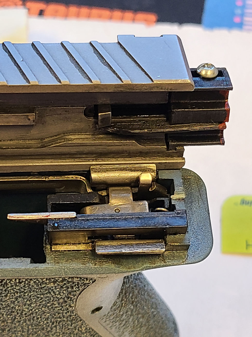 Here you can see the blade of the Glock switch extending under the slide. Below is the frame, where you can see the trigger bar that the blade will interact with.