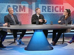 In einem Fernsehstudio sitzen fünf Personen am Diskussionstisch, dahinter zeigen Pfeile mit den Worten "Arm" und "Reich" in entgegengesetzte Richtungen