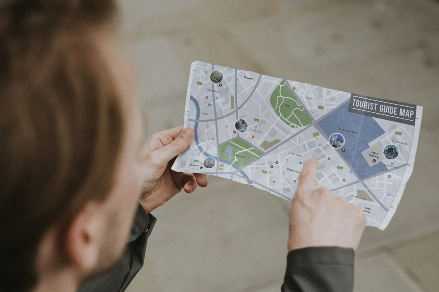 Person hält einen Stadtplan in den Händen und zeigt mit dem Finger auf einen markierten Ort