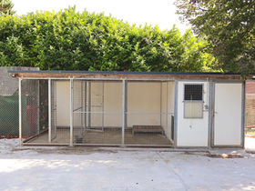 Kennel façade with a door and window, opening onto a covered fenced run.