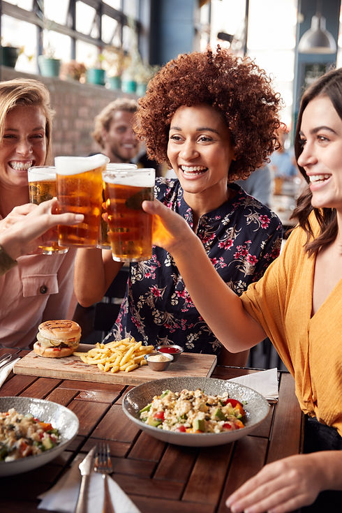 Four Young Female Friends Meeting For Drinks And Food Making A Toast In Restaurant.jpg