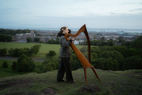 girl playing arp in top of Arthur seat photography session in scotland