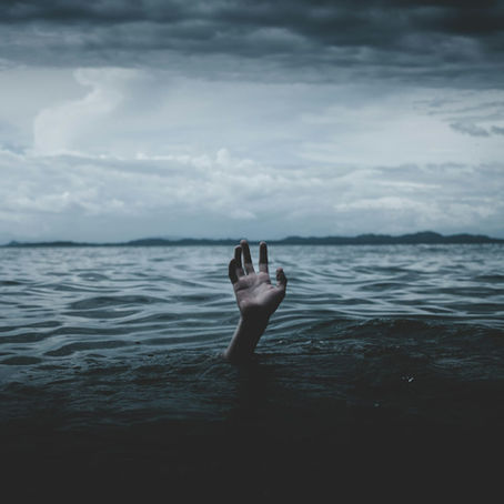 A hand sticking out of dark ocean water on a dark and stormy day