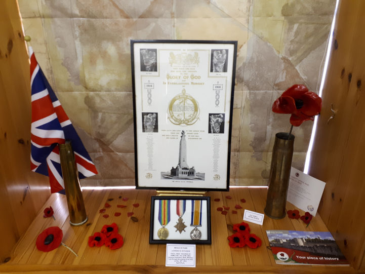 Photograph showing an exhibition display of World War 1 memorabilia including a British flag, medals and a red poppy.