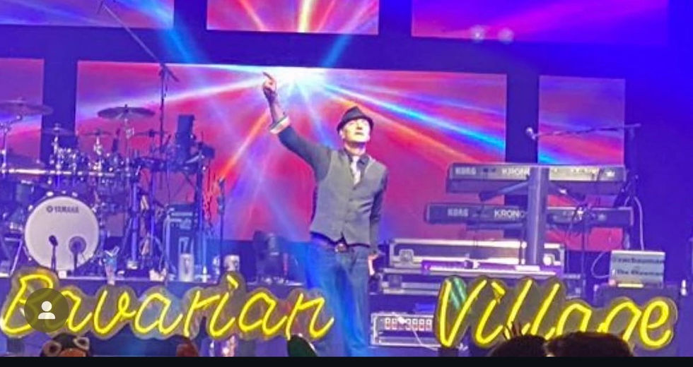 Performer on stage with colorful lights and text.