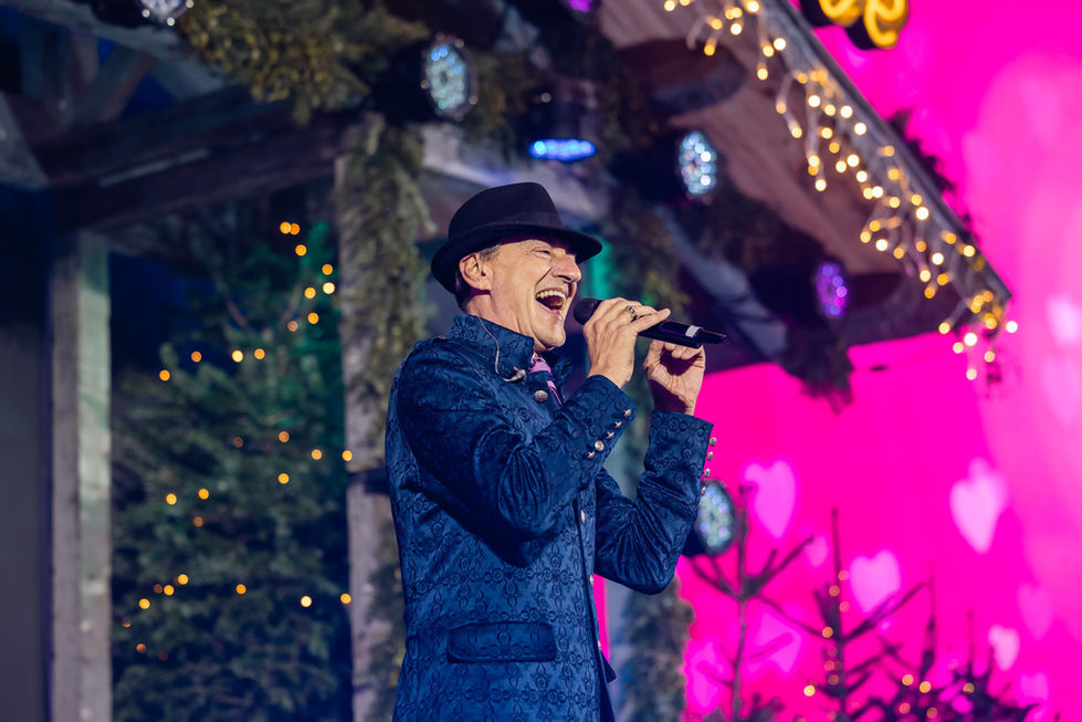 Singer performing on a decorated stage with microphone.