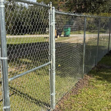 Exterior view. Newly installed galvanized chain link fence with single gate.