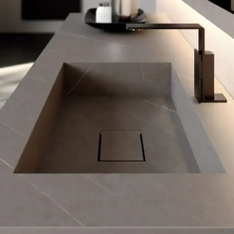 Modernes Waschbecken-Design: In die Waschtischplatte integriertes Becken in Beton-Optik mit eleganter, dunkler Armatur – exklusive Badausstattung von BAD ELEMENTE Hamburg.