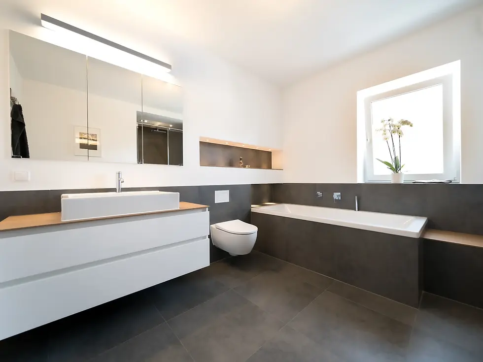 Modernes Badezimmer-Design mit weißem Waschtisch, großem Spiegelschrank und integrierter Badewanne – Beispiel für eine sorgenfreie, schlüsselfertige Badsanierung in Hamburg von BAD ELEMENTE.