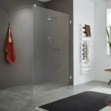 Minimalistische Walk-In Dusche mit einer einzelnen, feststehenden Glaswand und bodengleichem Einstieg – modernes Bad-Ambiente von BAD ELEMENTE.