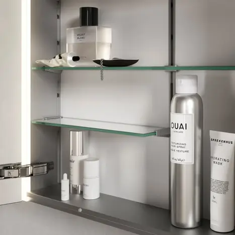 Blick in den perfekt organisierten Innenraum eines Spiegelschranks mit verstellbaren Glasfachböden für Kosmetik und Pflegeprodukte – BAD ELEMENTE.