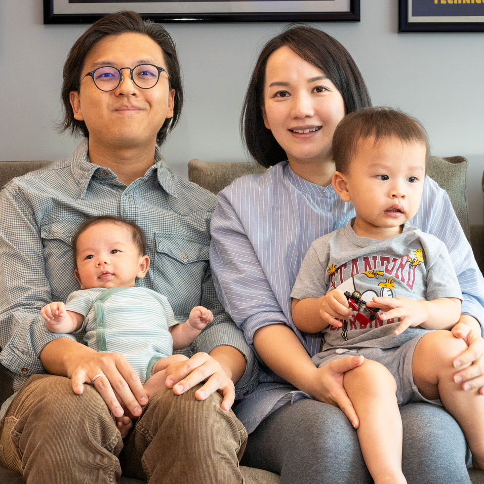 a family sits on a couch with two children one of whom is wearing a shirt that says ucla