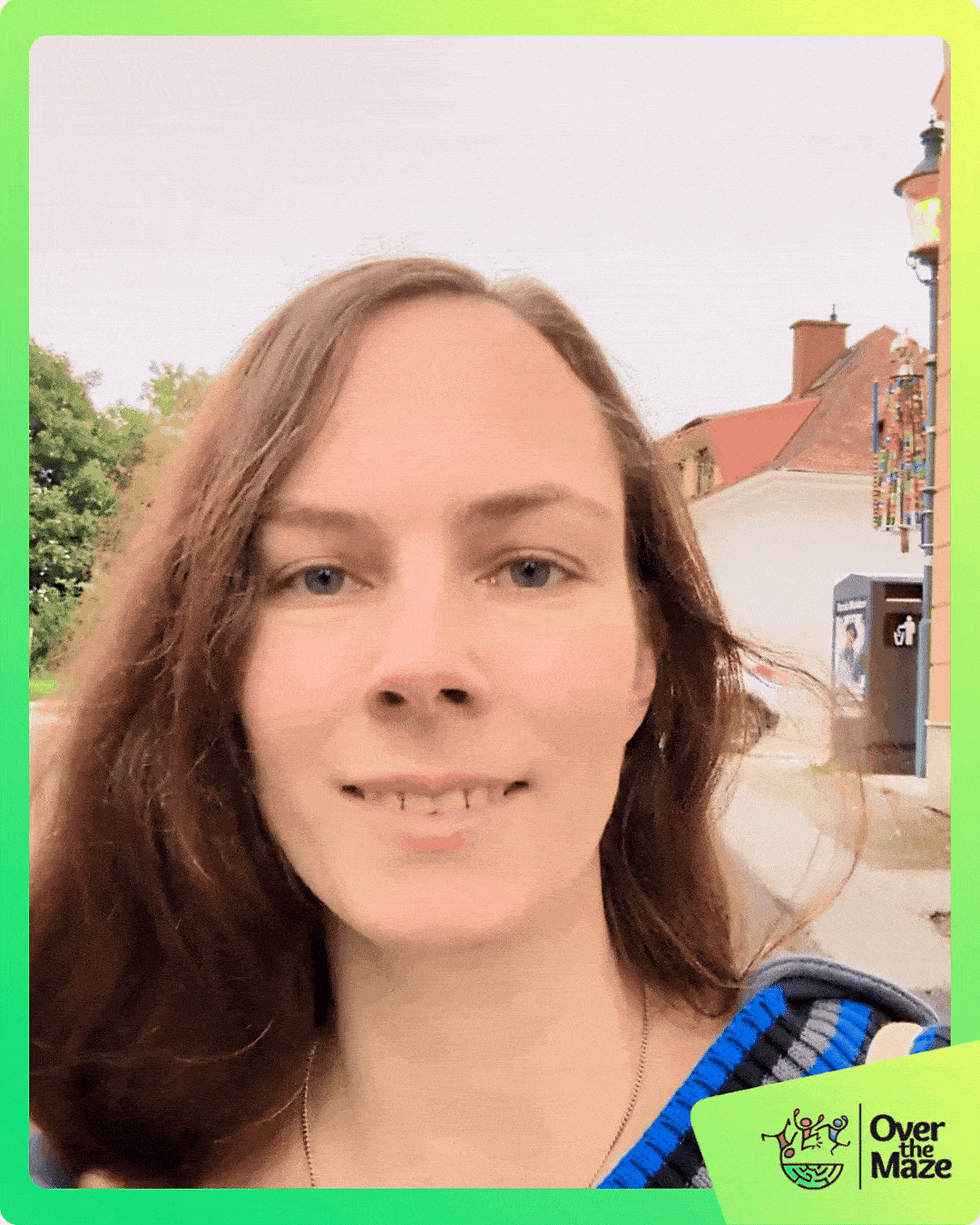 Woman smiling outdoors with buildings in the background. Green border with “Over the Maze” logo in the corner. Bright, cheerful mood.