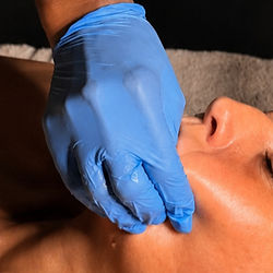 Client receiving a buccal facial massage for sculpting and tension release
