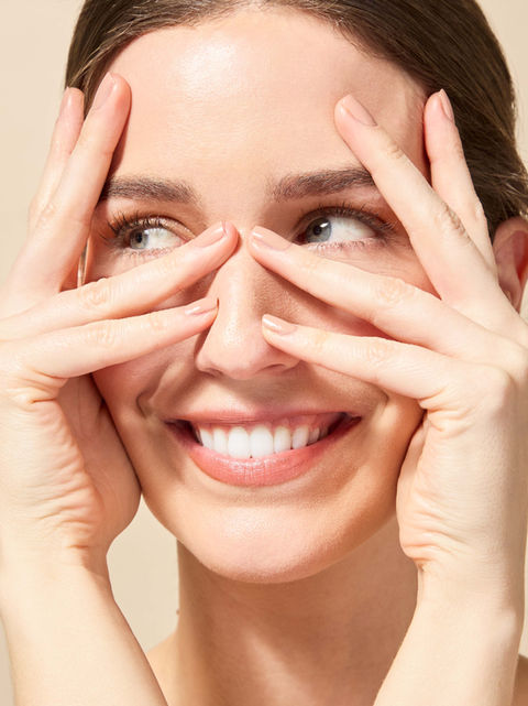 model with hands framing face laughing
