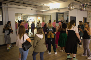 party at The Skate Sanctuary - some people are wearing roller skates, others are not.  Discoballs and mirrors in the background