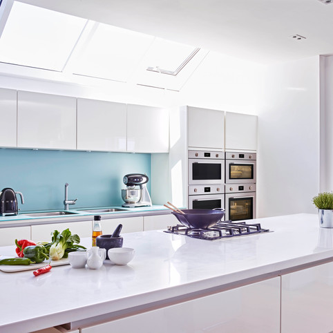 שיש לבן ובוהק הפרוס לכל אורכו של מטבח אלגנטי ולבן בוהק אף הוא ומשלים אותו לעיצוב מרהיב ושובה לב