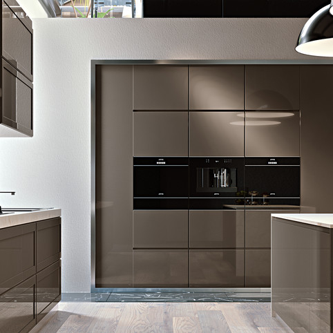 מטבח מודרני בצבע אפור עכבר, אשר שולבו בו סט תנורי אפיה של סמג מזכוכית שחורה ומקרר סמג דווקא בצבע נירוסטה בהיר, המתכתב עם משטחי העבודה הבהירים שעל שני איי המטבח