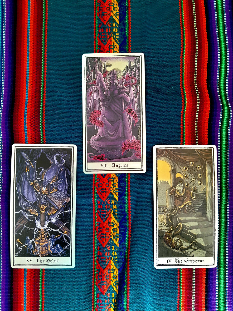 Trois cartes de tarot sur tissu bleu rayé: Le Diable, Justice et L’Empereur, ambiance mystique.