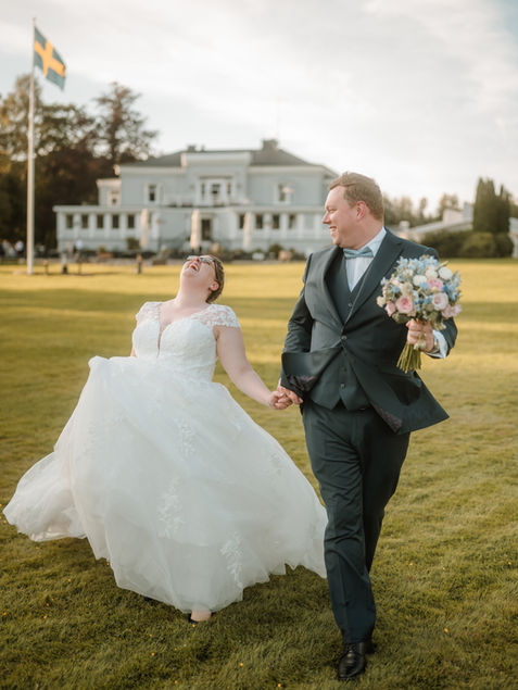 Brautpaar rennt über die Wiese an ihrer Hochzeit in Schweden.