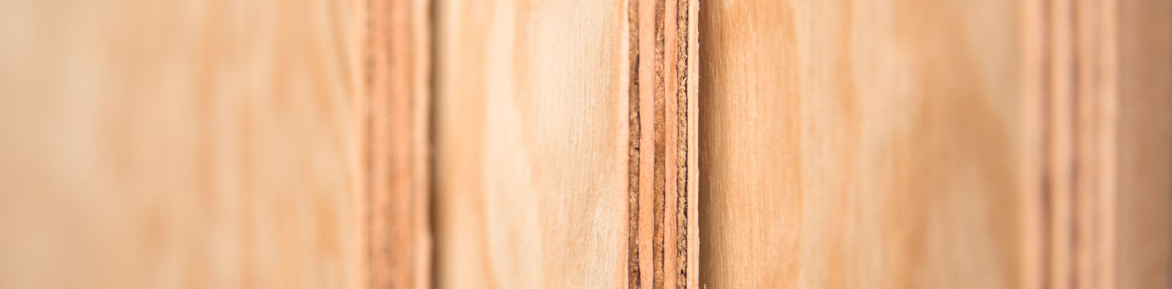 Nahaufnahme gestapelter Sperrholzplatten, Kanten zeigen die einzelnen Holzschichten.