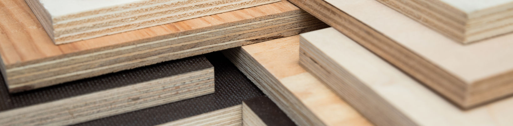 Stapel von Sperrholzplatten in verschiedenen Holzarten und Dicken.