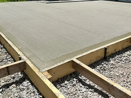 A freshly poured and drying concrete slab is still held together by wooden support forms.