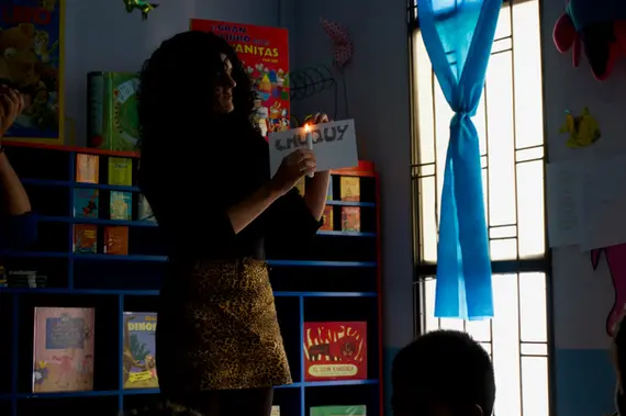 Mujer sostiene cartel de Jujuy con vela en taller educativo.