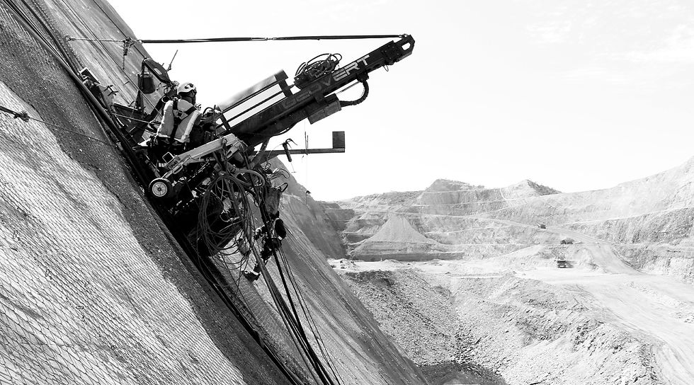 Highwall stabilisation works with rockfall mesh and high-reach drilling in a mining environment.