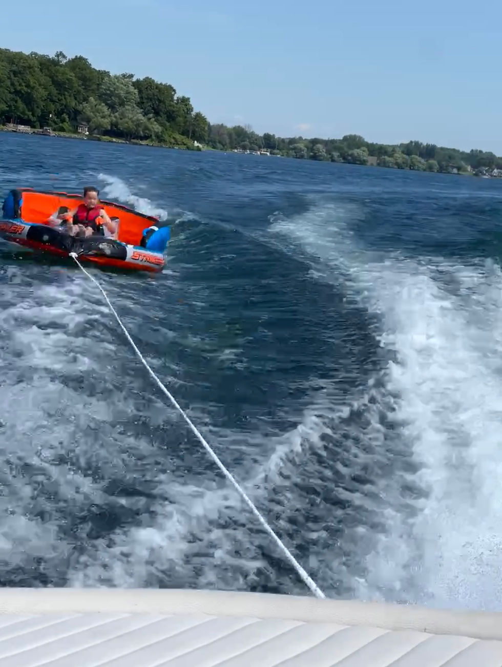 Kid tubing behind a boat on the St. Lawrence River in Cornwall, Ontario, showcasing family-friendly waterfront living.
