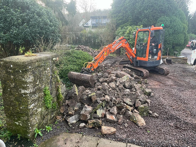 Orange tractor breaking down a stone wall
