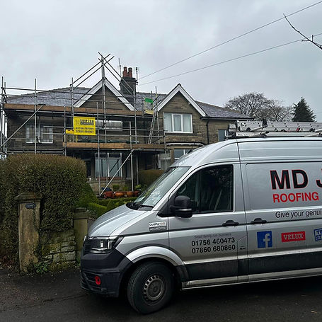 A van is parked in front of a house that is surrounded by scaffolding, indicating ongoing construction or renovation work.