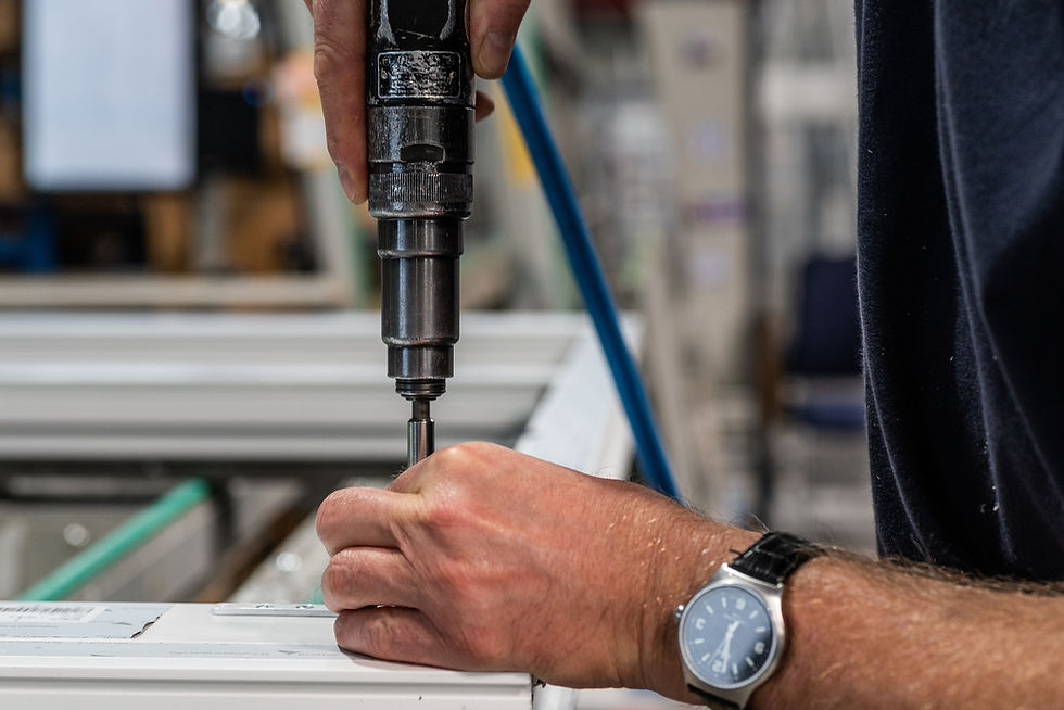 A photo of schlüters manufacturing facility showing a worker with hand drill inserting screws for the production of a window