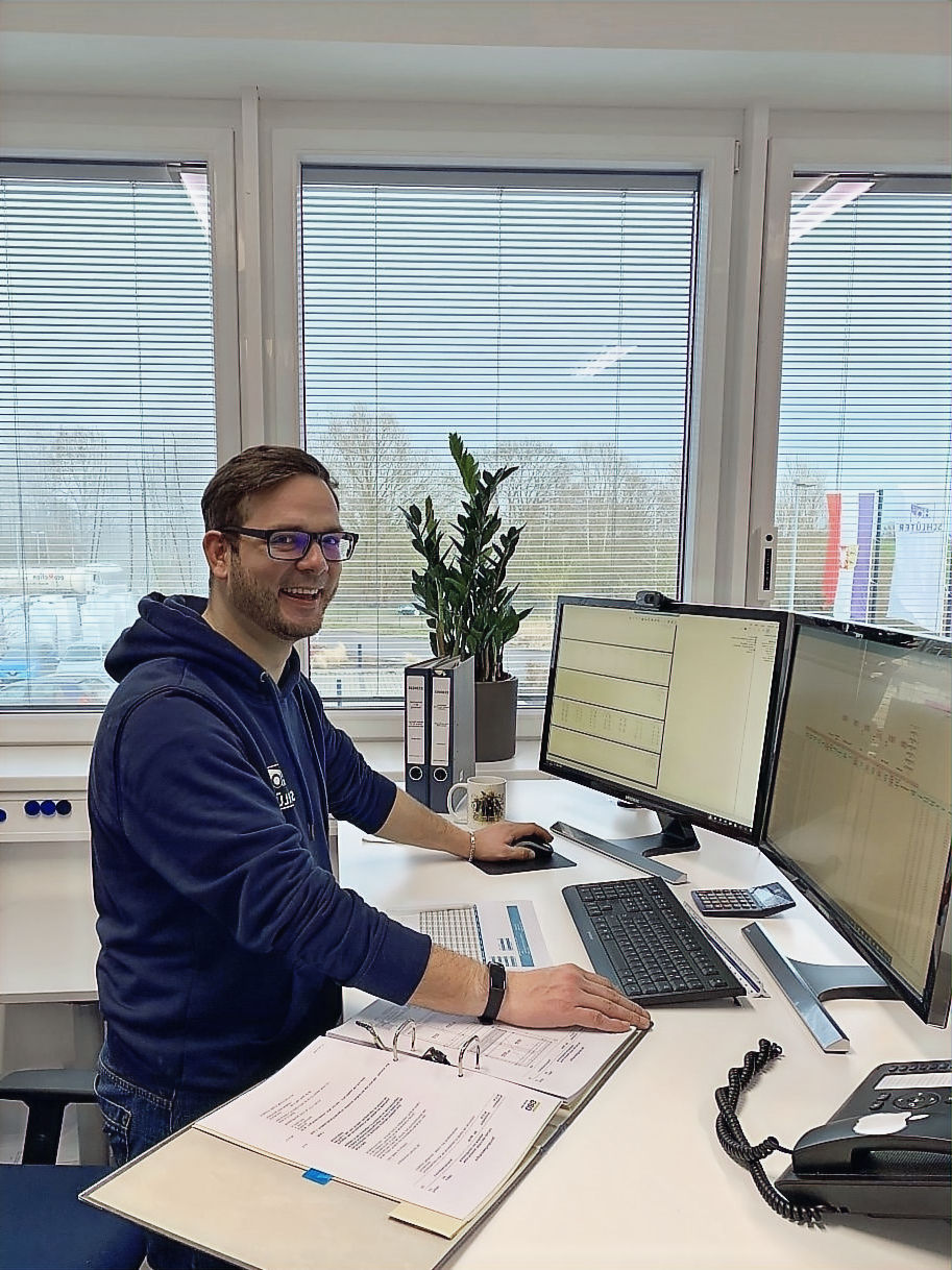 A photo of an employee standing at a computer in our planning department.