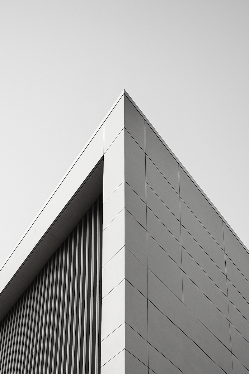 Architectural photograph featuring clean lines, geometric precision, and upward momentum—the sharp edge of a contemporary building against a clear sky.