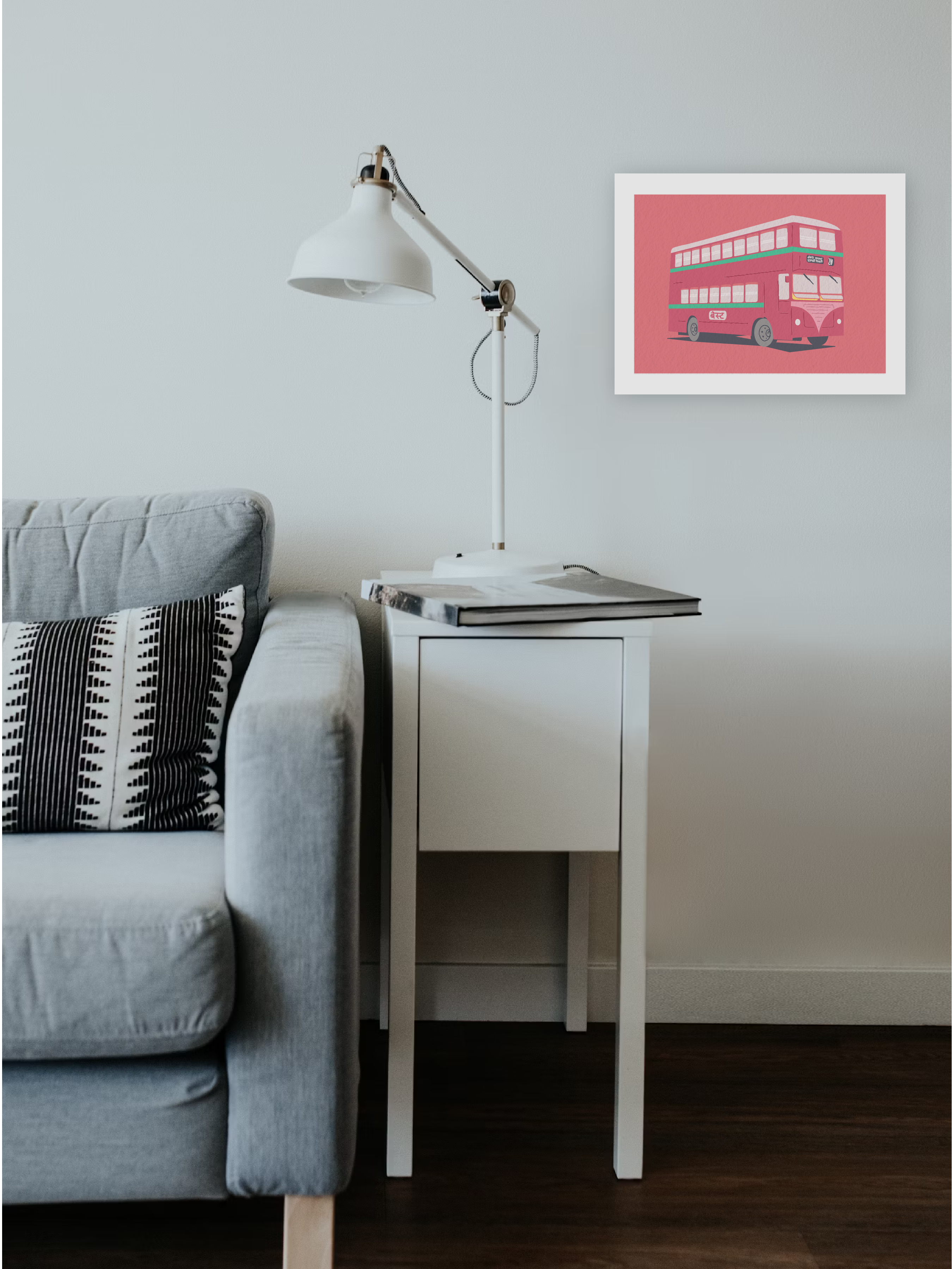 A framed poster on a wall in a house containing the illustration of a double decker bus