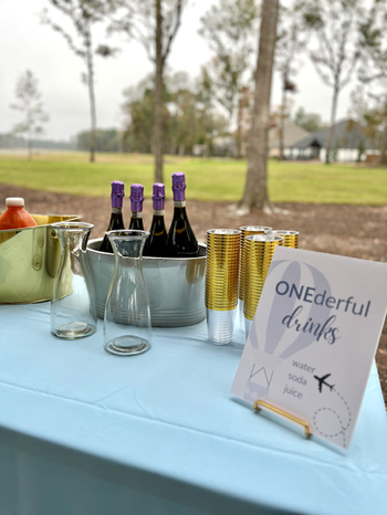 ONEderful World drink display with gold-rimmed cups, beverage carafes, and custom drink signage.