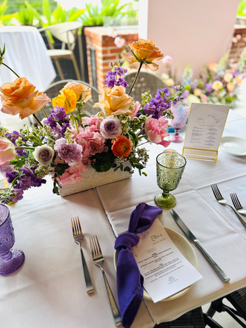 Luxury birthday brunch tablescape featuring floral centerpieces, custom drink signage, and elegant place settings.